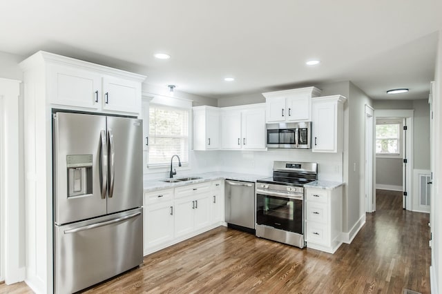 kitchen featuring decorative backsplash, light stone counters, stainless steel appliances, sink, and white cabinetry