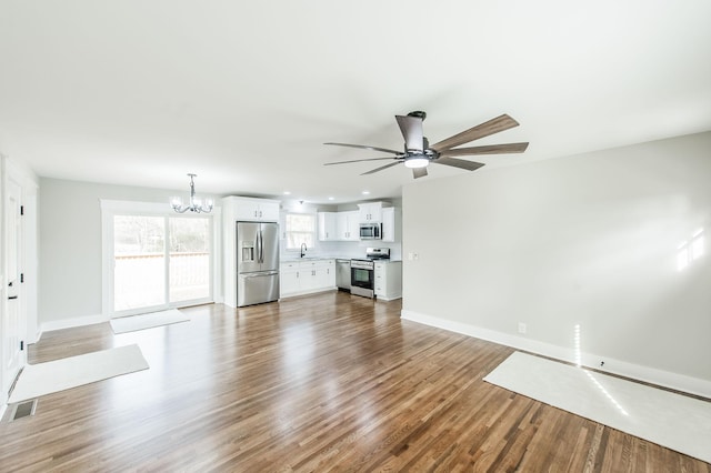 unfurnished living room with hardwood / wood-style floors, ceiling fan with notable chandelier, and sink