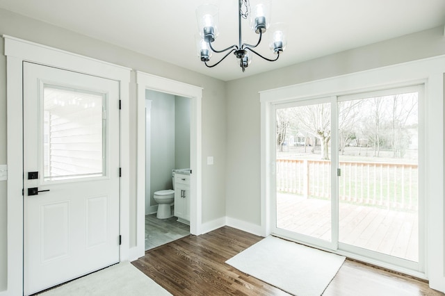 doorway with a notable chandelier and wood-type flooring