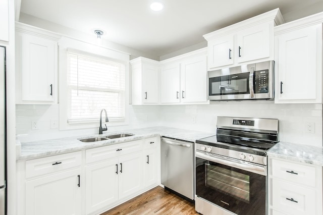 kitchen with appliances with stainless steel finishes, light hardwood / wood-style flooring, white cabinetry, and sink