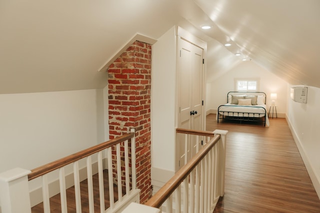 corridor with vaulted ceiling and hardwood / wood-style flooring