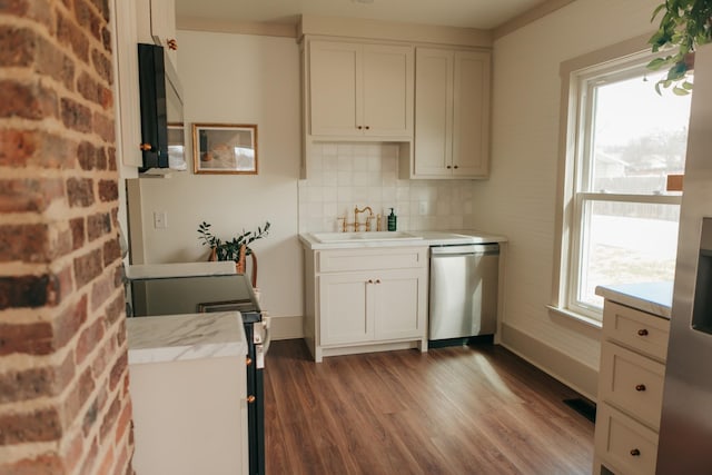 kitchen with tasteful backsplash, stainless steel dishwasher, sink, white cabinets, and range