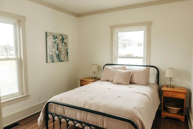 bedroom with multiple windows and dark hardwood / wood-style flooring