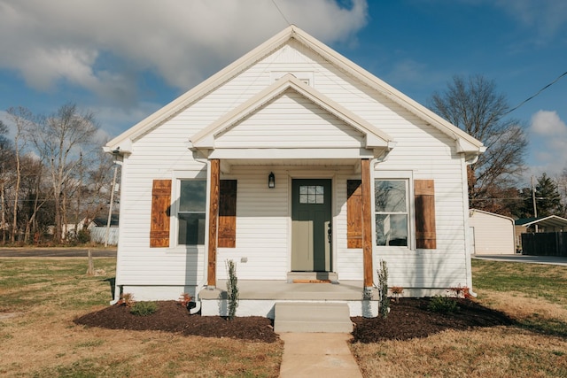 bungalow-style home featuring covered porch and a front lawn