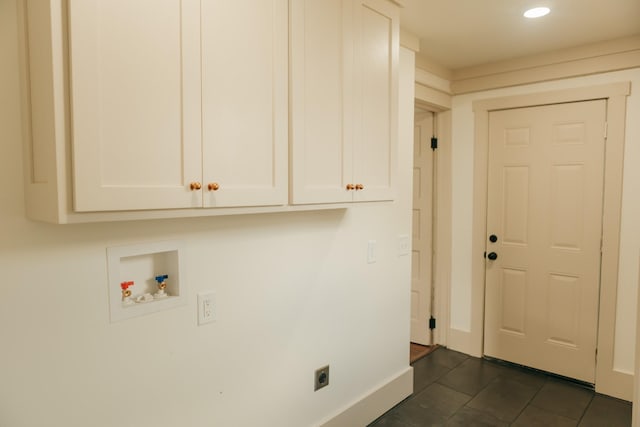 clothes washing area with hookup for an electric dryer, washer hookup, dark tile patterned floors, and cabinets