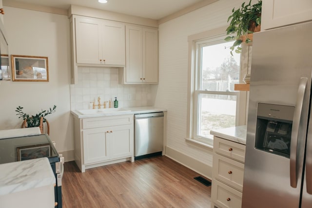 kitchen featuring white cabinetry, decorative backsplash, sink, and stainless steel appliances