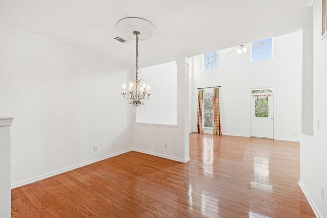 empty room featuring light hardwood / wood-style flooring and ceiling fan with notable chandelier