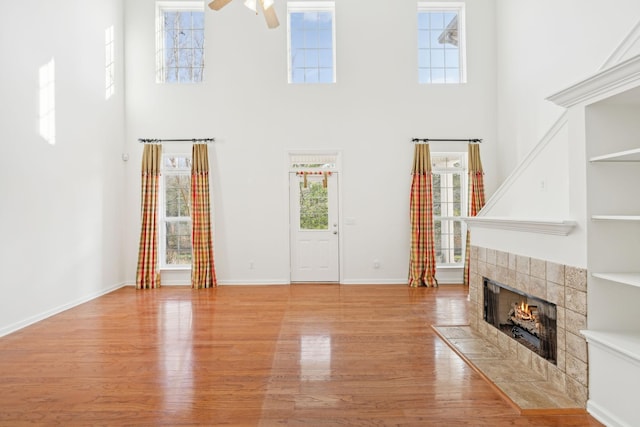 unfurnished living room with plenty of natural light, ceiling fan, a towering ceiling, and a fireplace