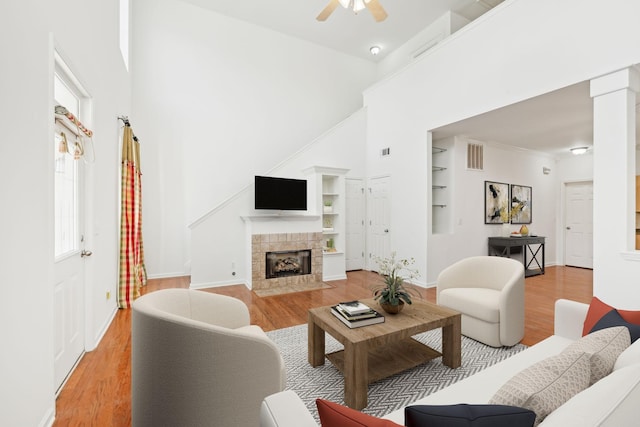 living room with built in shelves, light hardwood / wood-style flooring, and a high ceiling