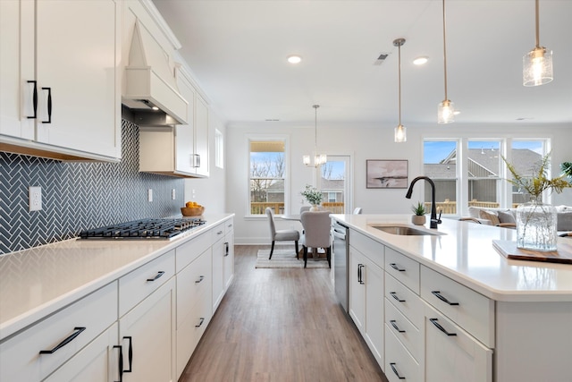 kitchen with decorative light fixtures, stainless steel appliances, white cabinetry, and sink