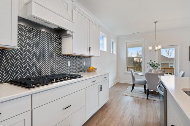 kitchen with appliances with stainless steel finishes, tasteful backsplash, custom range hood, pendant lighting, and white cabinetry