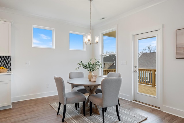 dining area featuring a notable chandelier, visible vents, ornamental molding, light wood-type flooring, and baseboards