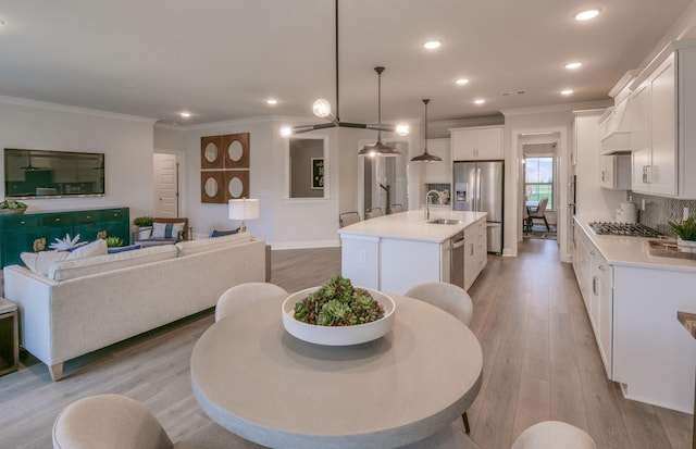 kitchen featuring appliances with stainless steel finishes, sink, pendant lighting, white cabinets, and an island with sink