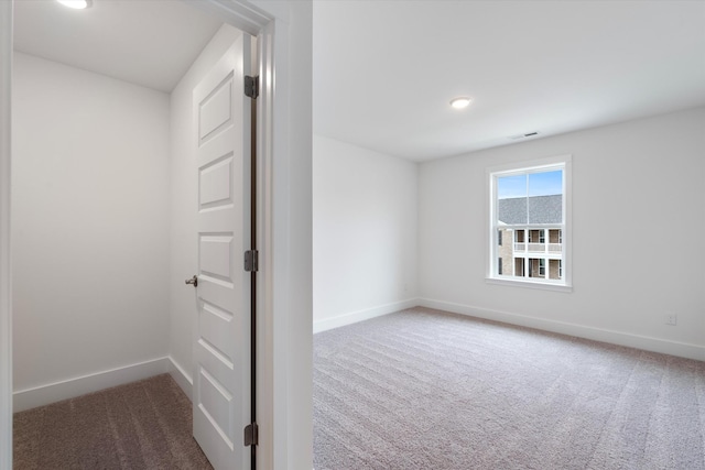 carpeted spare room with visible vents and baseboards