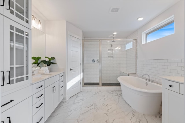 bathroom with vanity, shower with separate bathtub, and tile walls