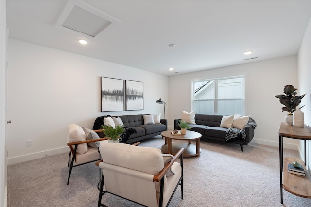 living area with light carpet, visible vents, attic access, and baseboards