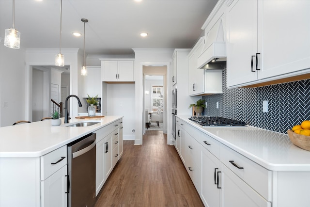 kitchen featuring appliances with stainless steel finishes, sink, pendant lighting, white cabinets, and an island with sink