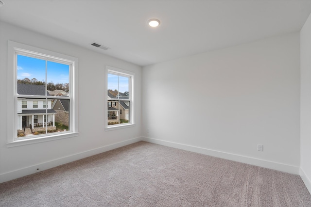 carpeted empty room featuring visible vents and baseboards