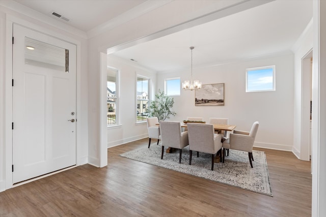 dining space featuring hardwood / wood-style floors, an inviting chandelier, and ornamental molding