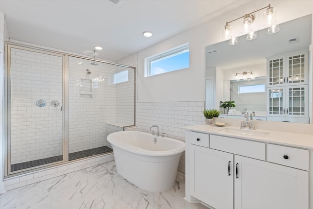 bathroom featuring vanity, visible vents, marble finish floor, a soaking tub, and a stall shower