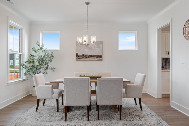 dining space with wood-type flooring, an inviting chandelier, and ornamental molding