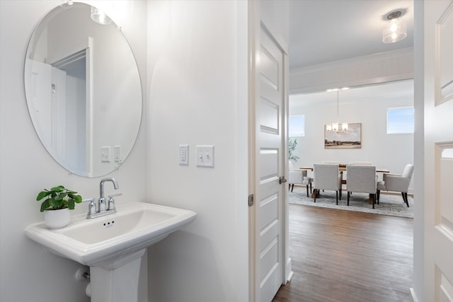 bathroom featuring wood-type flooring, ornamental molding, a notable chandelier, and sink