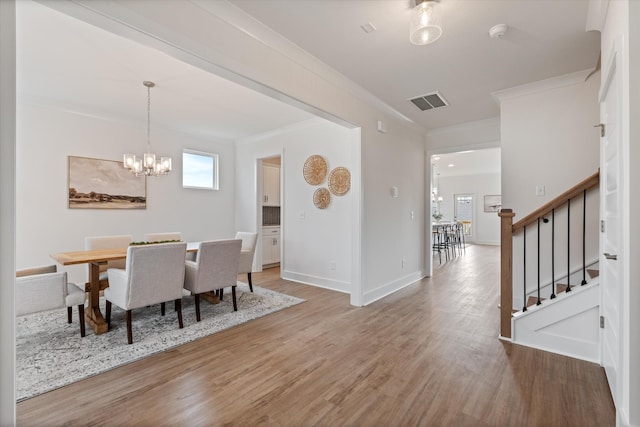 dining room with a chandelier, wood-type flooring, and ornamental molding