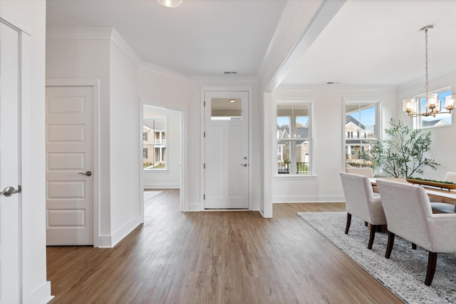 entrance foyer featuring hardwood / wood-style flooring, crown molding, and a chandelier