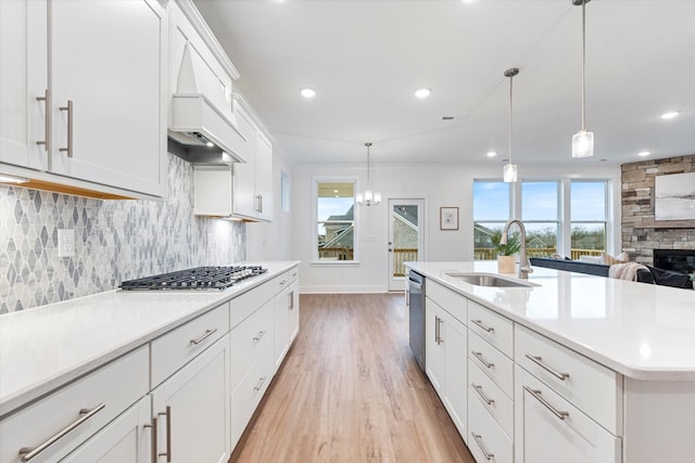 kitchen with a sink, light wood-style floors, light countertops, appliances with stainless steel finishes, and backsplash