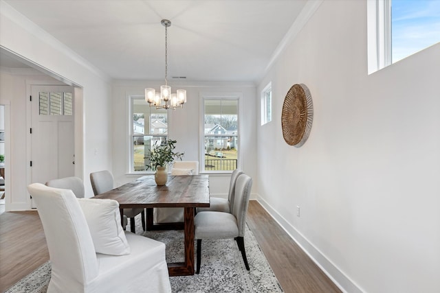 dining area with ornamental molding, an inviting chandelier, baseboards, and wood finished floors