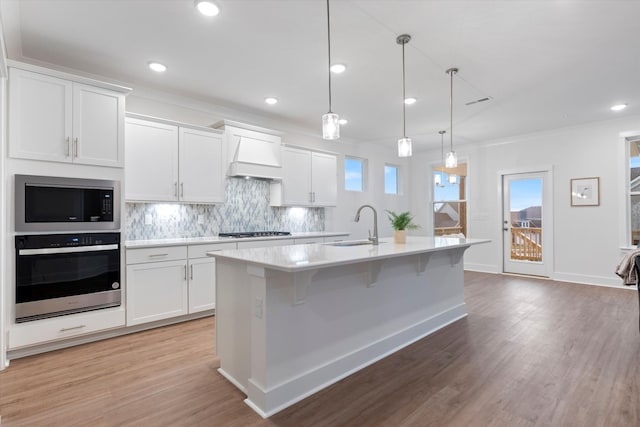 kitchen featuring a sink, stainless steel appliances, custom exhaust hood, and light countertops