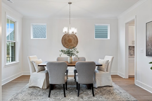 dining area featuring crown molding, a notable chandelier, baseboards, and wood finished floors