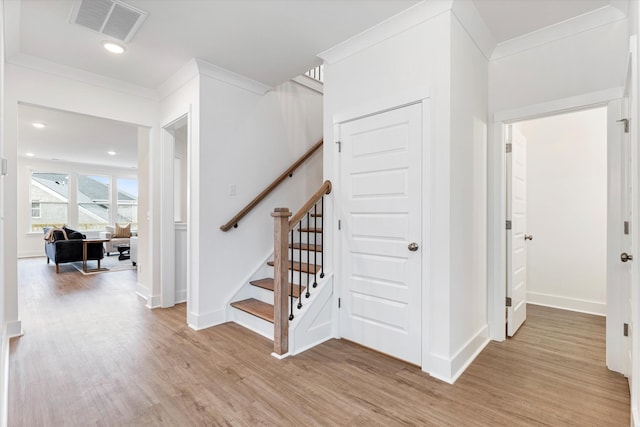 stairway featuring ornamental molding, visible vents, baseboards, and wood finished floors