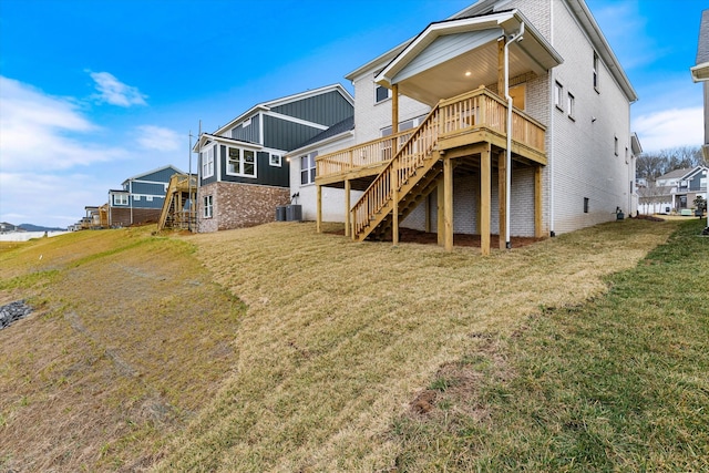 rear view of property with brick siding, stairs, a lawn, and a wooden deck