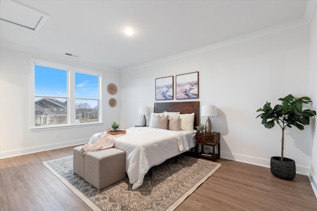 bedroom with visible vents, baseboards, crown molding, and wood finished floors