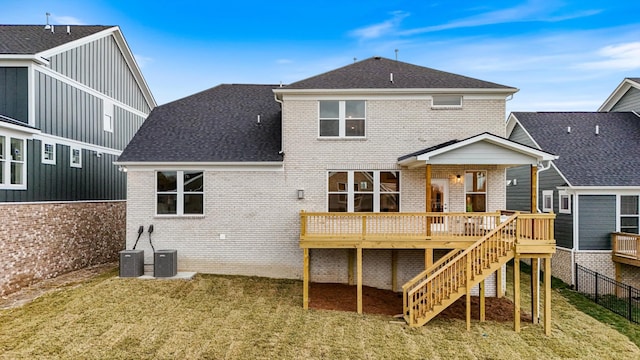 back of house with a lawn, roof with shingles, stairs, a deck, and brick siding