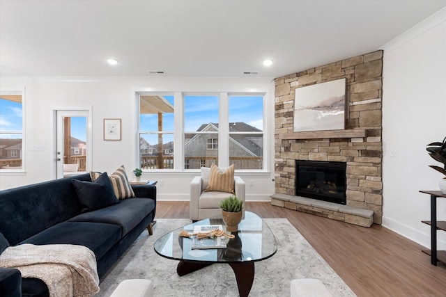 living room featuring plenty of natural light, a fireplace, wood finished floors, and visible vents