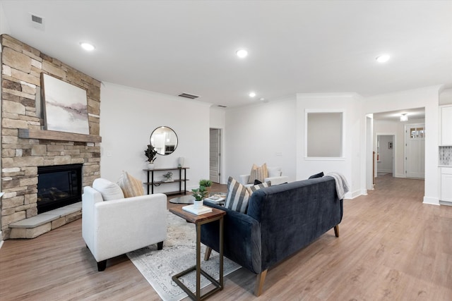 living area with light wood finished floors, a fireplace, visible vents, and crown molding