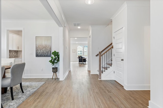 foyer with light wood-style flooring, stairway, visible vents, and crown molding