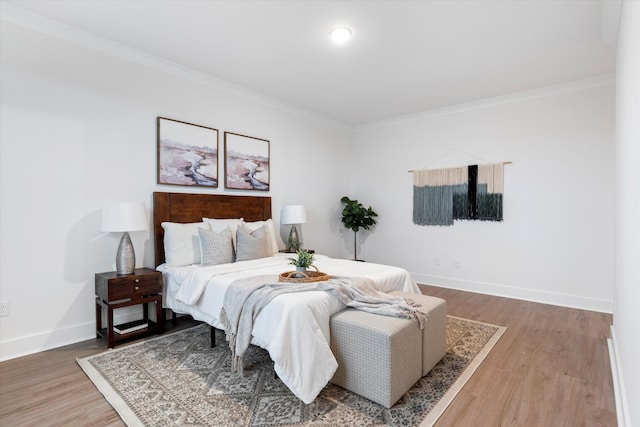 bedroom with light wood finished floors, ornamental molding, and baseboards