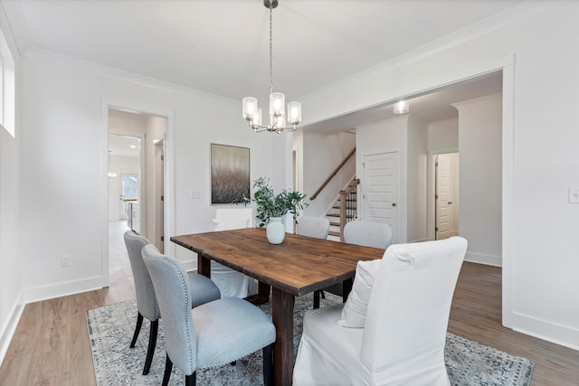 dining area featuring baseboards, an inviting chandelier, wood finished floors, and crown molding