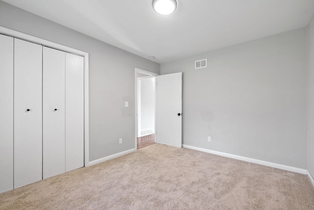 unfurnished bedroom featuring a closet and light colored carpet