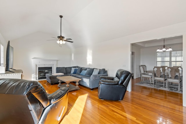 living room featuring a high end fireplace, wood-type flooring, and ceiling fan with notable chandelier