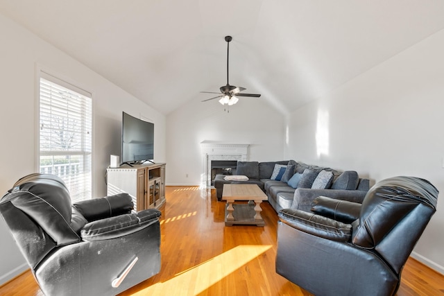 living room featuring ceiling fan, a fireplace, lofted ceiling, and light hardwood / wood-style flooring