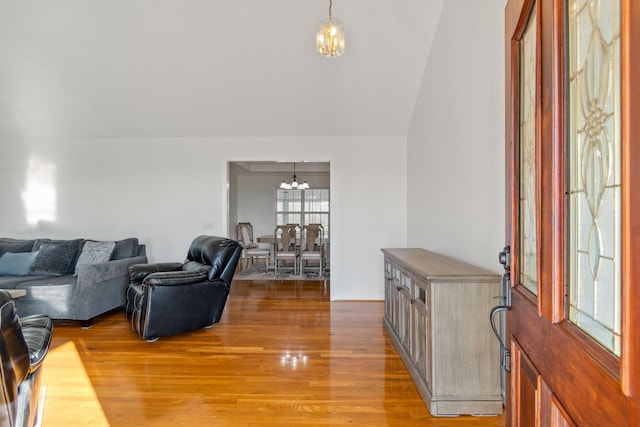 living room with wood-type flooring, vaulted ceiling, and an inviting chandelier