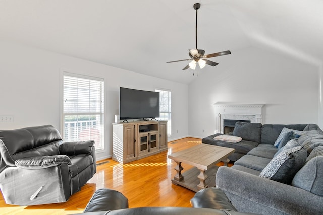 living room featuring a fireplace, light hardwood / wood-style floors, ceiling fan, and lofted ceiling