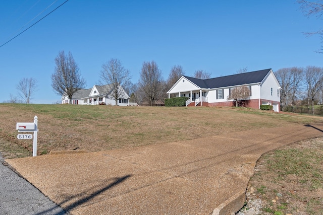 ranch-style house featuring covered porch and a front yard