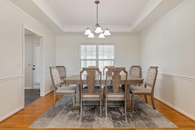 dining room featuring a chandelier, hardwood / wood-style flooring, and a raised ceiling