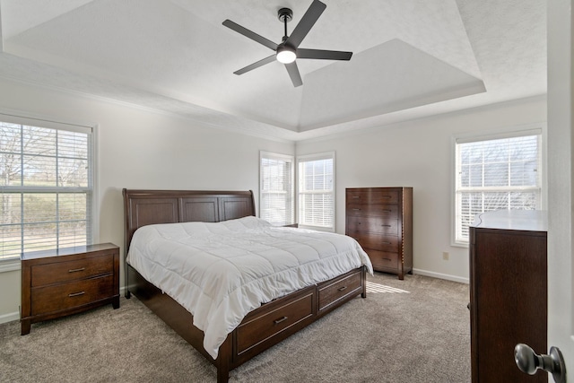 carpeted bedroom featuring a tray ceiling, multiple windows, and ceiling fan