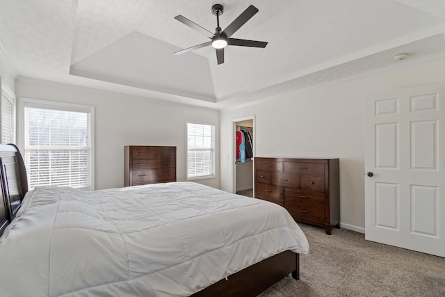 carpeted bedroom featuring a raised ceiling, a spacious closet, a closet, and ceiling fan